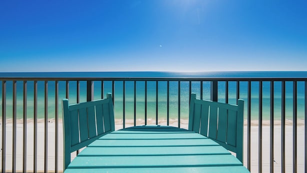 A view from a balcony overlooking a beach with a clear sky and calm sea.