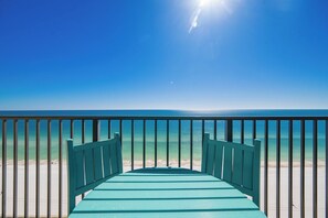 Vista desde un balcón sobre una playa con cielo despejado y mar tranquilo.