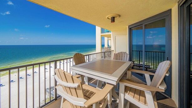 A balcony with a view of the ocean, a table, and chairs. - GREAT BEACH FRONT VIEW from this 2 Bedroom at Phoenix 3 (Orange Beach)