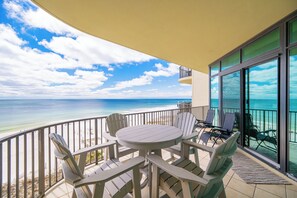 Ein Balkon mit Tisch und Stühlen, der Blick auf einen Strand und das Meer bietet.