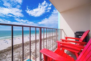 Un balcone con vista sulla spiaggia, sedie rosse e una piscina.