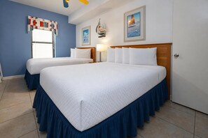 Ett hotellrum med två sängar, ett fönster med persienner, en vägglampa och en inramad tavla.