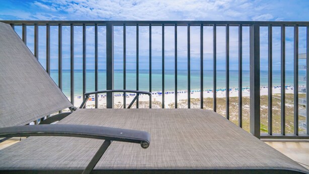 A balcony with a view of the beach and ocean.