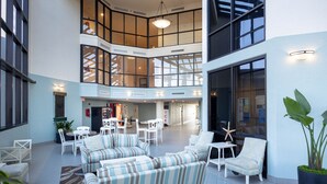 A spacious indoor area with multiple seating arrangements, including sofas and chairs, and a large potted plant.