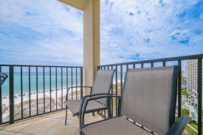 Ein Balkon mit Sitzgelegenheiten mit Blick auf Strand und Poolbereich.