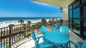 A balcony with a view of the beach, a pool, and a dining area with chairs. - Phoenix West 305 Your Coastal Getaway! (Orange Beach)