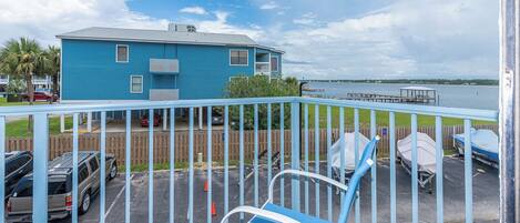 A blue building with a fenced parking area, a covered boat dock, and a view of the water.