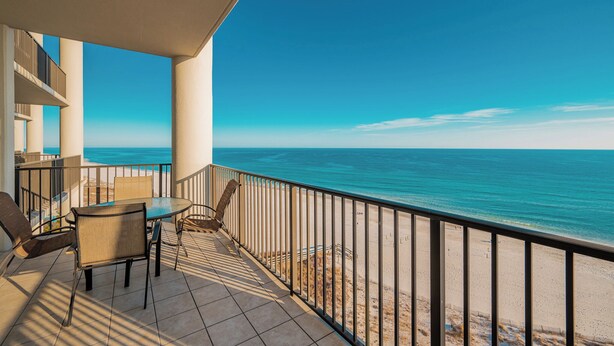Un balcon avec vue sur l’océan, une table et des chaises.