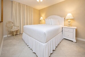 A neatly arranged bedroom with a bed, nightstands, a chair, and curtains.
