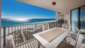 A balcony with a view of the beach and ocean.
