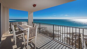 Ein Balkon mit Tisch und Stühlen, der Blick auf einen Strand und eine freie Meerblick bietet.