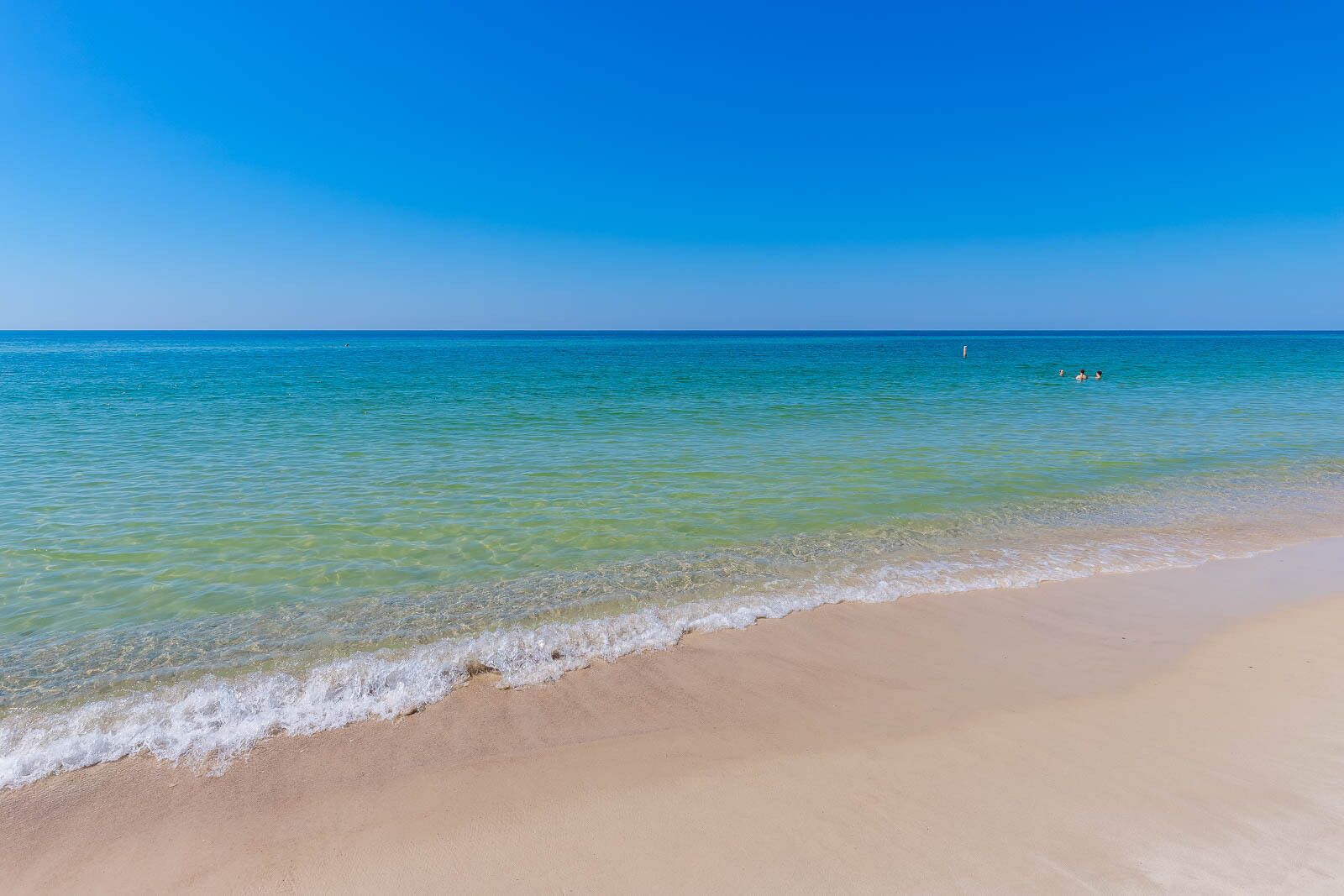 Uma praia com águas azul-claras e uma orla arenosa.