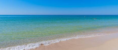 Uma praia com águas azul-claras e uma orla arenosa.