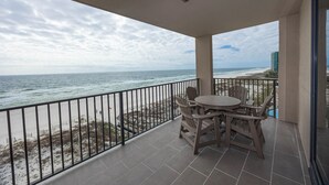 A balcony with a view of the beach and ocean.