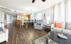 A spacious living area with a dining table, chairs, a sofa, and a coffee table. - 5th Floor ~ 3 Bedroom Condo~ Next to Flora-Bama ~ Popular Choice! (Orange Beach)