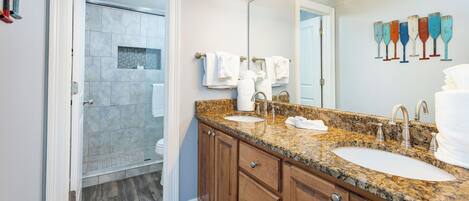 A bathroom with two sinks, a large mirror, and a shower area.