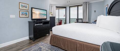 Een slaapkamer met een groot bed, een plafondventilator, een televisietoestel en uitzicht op de omgeving.