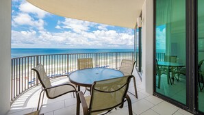A balcony with a round table and chairs, overlooking a beach and the ocean. - ~Beach Front~ 2 Bedroom @ Phoenix IX (Orange Beach)