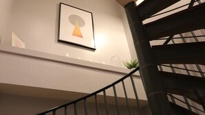 Un escalier en colimaçon avec une rampe noire menant à un palier.