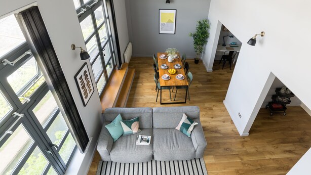 Un salon moderne avec un canapé gris, un plancher en bois et de grandes fenêtres.