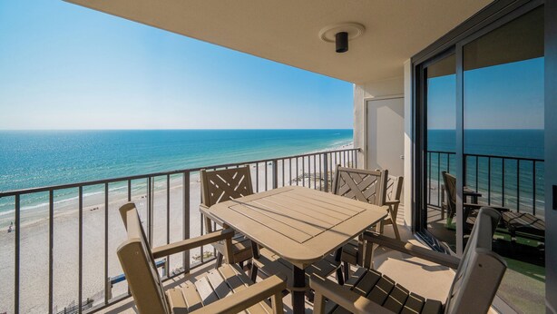 A balcony with a table and chairs overlooking a beach. - BEST time for the BEACH! 1BR @ Phoenix 3 (Orange Beach)