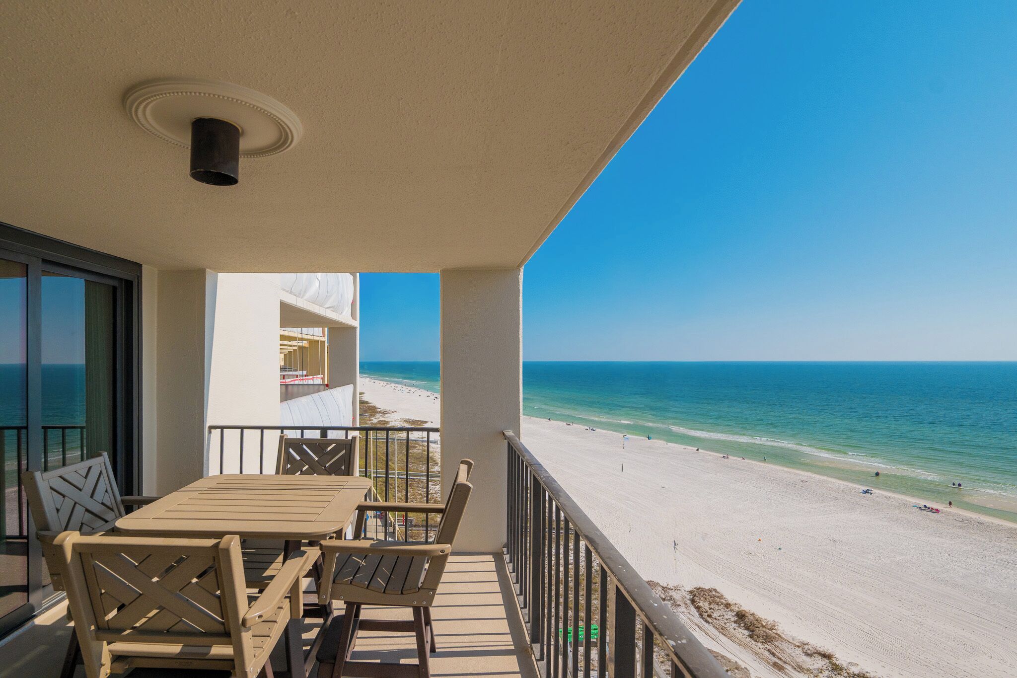 Un balcon avec une table et des chaises donnant sur une plage.