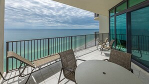 A balcony with a view of the ocean, furnished with chairs and a table. - Phoenix West - 3 Bedroom (Orange Beach)