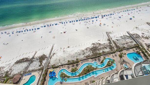 A beach resort with a large sandy beach, a swimming pool area, and a lifeguard tower. - Phoenix West - 3 Bedroom (Orange Beach)