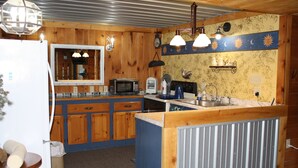 Una cocina compacta con armarios de madera, microondas, estufa y pileta.