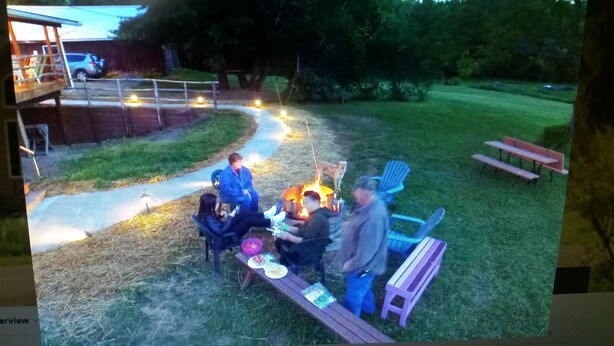Patio trasero con una chimenea, una mesa de picnic y un perro.