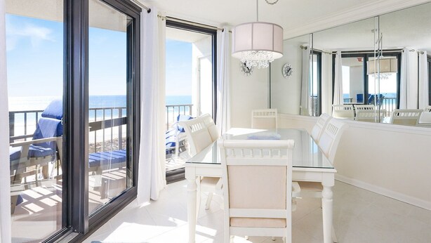 A balcony with a glass door, a table with chairs, and a chandelier.