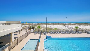 A pool area with a view of the beach, lounge chairs, and a lifeguard stand.