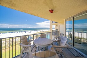 A balcony with a view of a beach, furnished with chairs and a table. - Reserved Parking with this Two Bedroom at Phoenix 5 (Orange Beach)