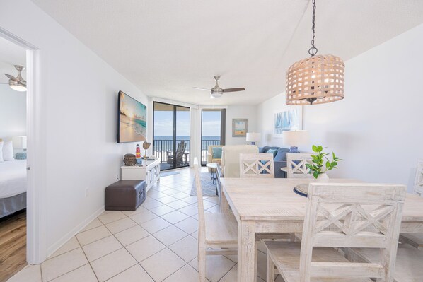 A spacious living area with a dining table, chairs, and a view of the ocean. - Reserved Parking with this Two Bedroom at Phoenix 5 (Orange Beach)