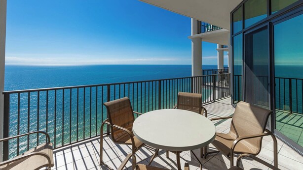A balcony with a view of the ocean, equipped with a table and chairs. - The Oasis at Orange Beach, formerly known as Phoenix West II, Unit 3006 (Orange Beach)