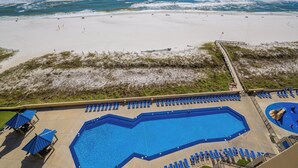 Vista de una playa con piscina, sillas de descanso y una torre de salvavidas.