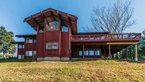 A modern two-story house with a prominent red facade, large windows, and a balcony. - The Tulip Tree Bay Lodge (Sparta)