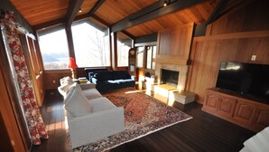 A cozy living room with a fireplace, a large TV, and a sofa. - The Tulip Tree Bay Lodge (Sparta)