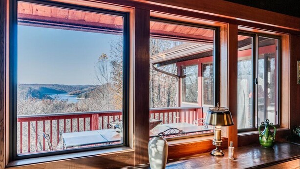 A wooden cabin with large windows offering a view of a lake and hills. - The Tulip Tree Bay Lodge (Sparta)