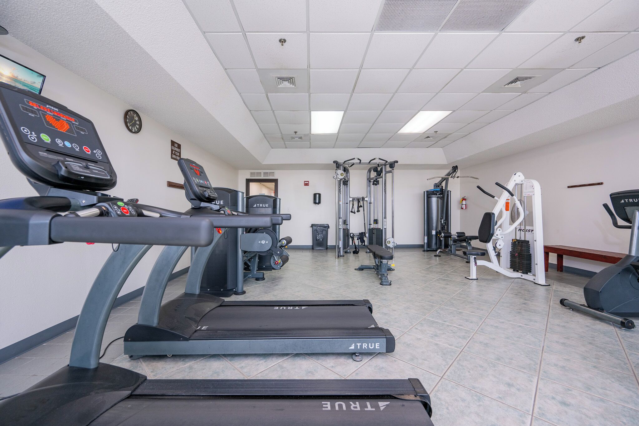 A gym with treadmills, weight machines, and a wall clock.