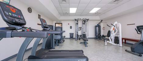 A gym with treadmills, weight machines, and a wall clock.