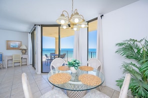 A dining area with a glass table, wicker chairs, and a ceiling light fixture.