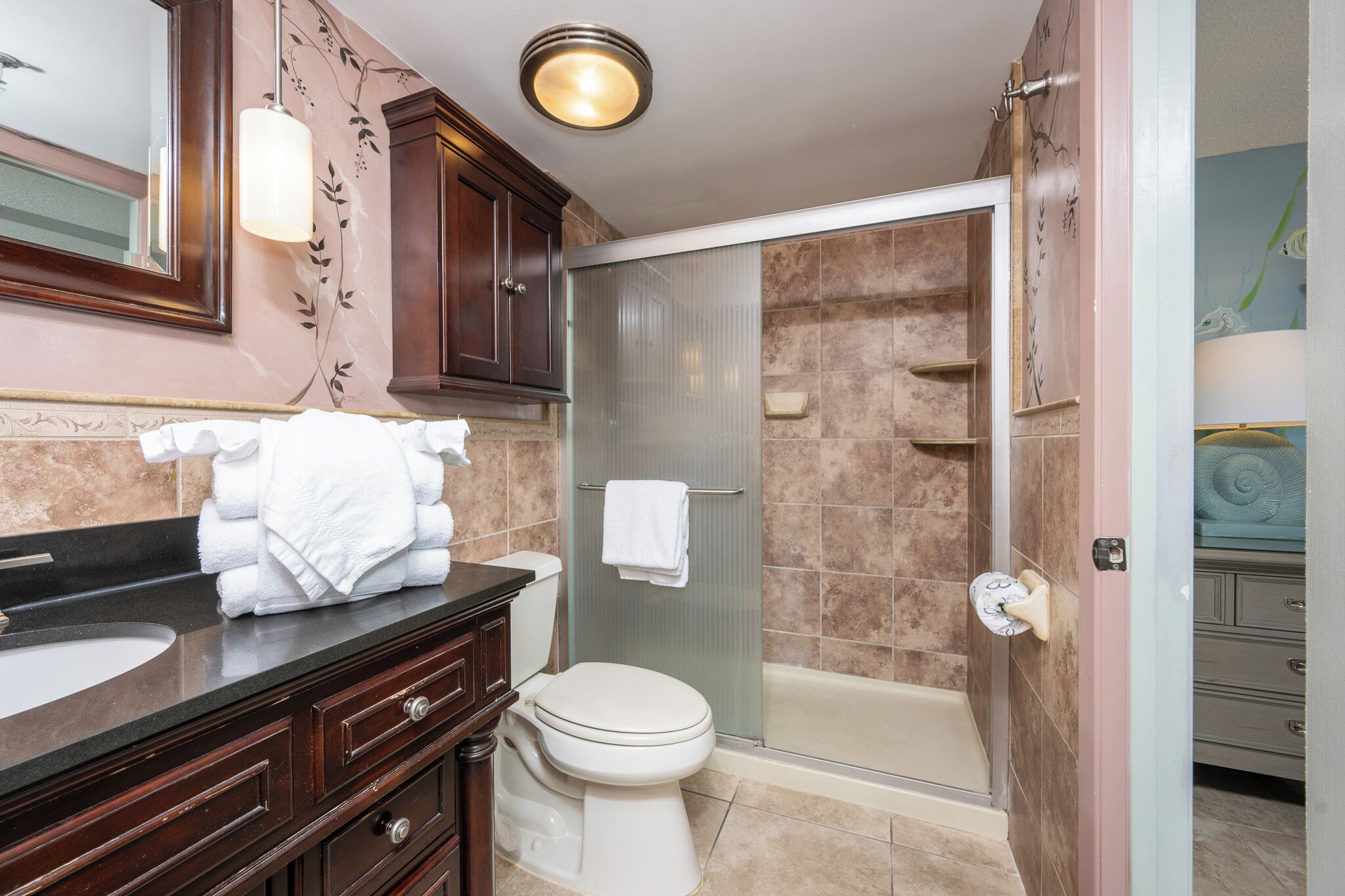 A bathroom with a vanity, toilet, shower, and a towel rack.