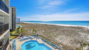 A hotel with a pool, beach view, and a high-rise building in the background.