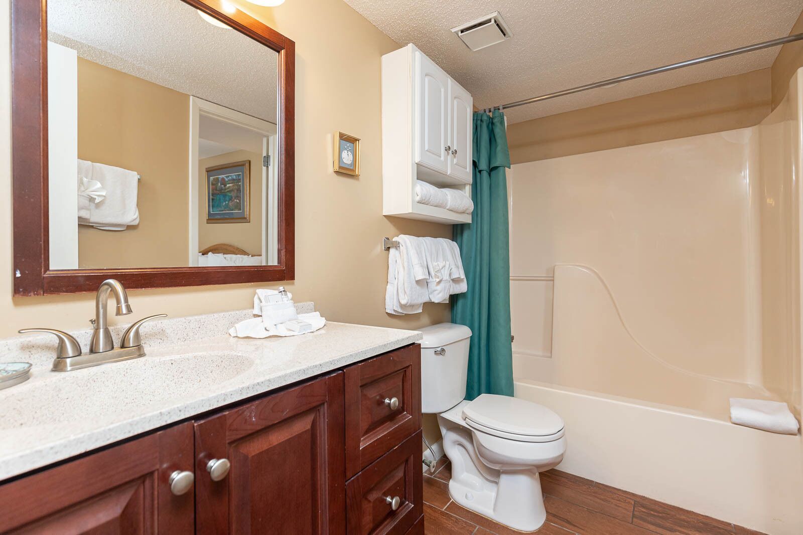 A bathroom with a sink, mirror, cabinet, toilet, and shower.