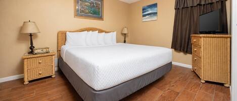 A bedroom with a bed, two nightstands, a dresser, a ceiling fan, and two wall-mounted paintings.