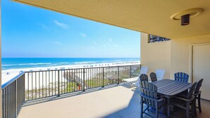 A balcony with a view of the beach, a table with chairs, and a door. - Everything is Better at the Beach! ~ Popular Two Bedroom @ Phoenix 2 (Orange Beach)