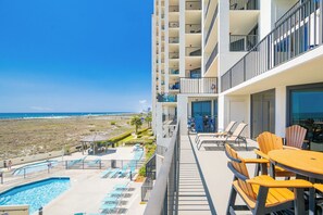 Ein Hotelbalkon mit Pool, Liegestühlen und Blick auf Strand und Meer.