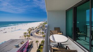 Un balcon donnant sur une plage, avec une table et des chaises.
