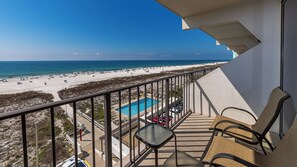 Un balcon avec piscine, vue sur la plage et espace salon extérieur.